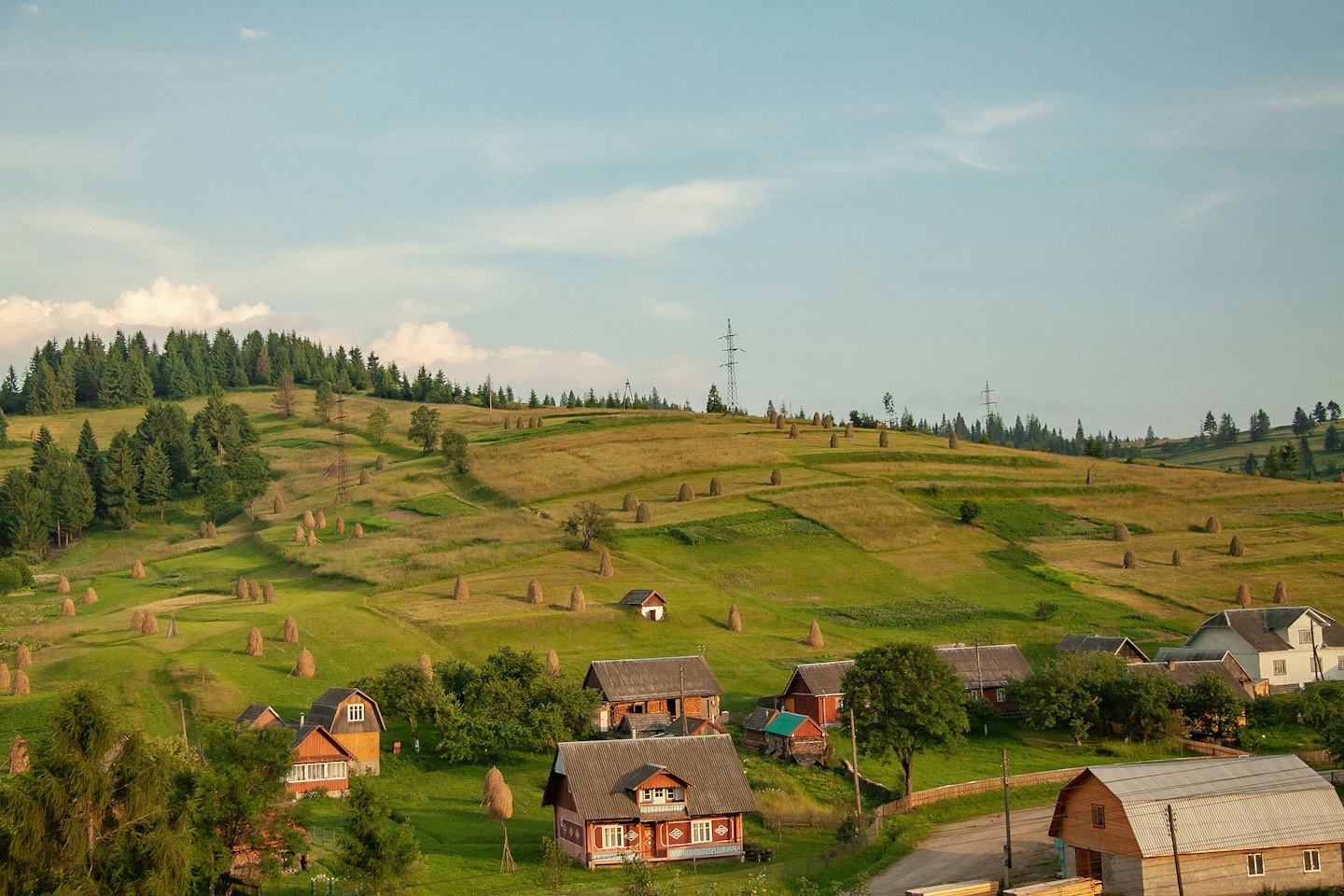 Traditional houses sit among rolling hills and rural haystacks.